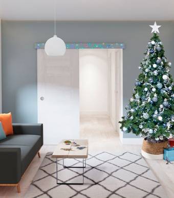 Sala de estar decorada com luzes de natal em cima da porta e uma árvore de natal